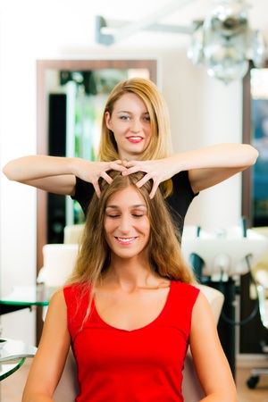 Woman at the hairdresser getting a head massage in the salon  の写真素材