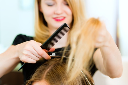 Woman at the hairdresser, she is cutting - close-up with selective focus on her hands  