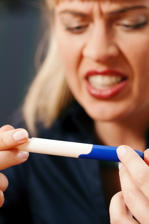 Woman looking at a pregnancy test being disappointed and angry upon the result の写真素材