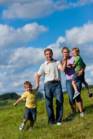 Happy family (father, mother and two sons) having a walk on a beautiful summer dayの写真素材
