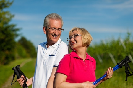 Nordic Walking - Happy mature or senior couple doing sports in summer outdoorsの写真素材
