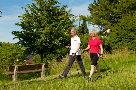 Nordic Walking - Happy mature or senior couple doing sports in summer outdoors Nordic Walking - Happy mature or senior couple doing sports in summer outdoors