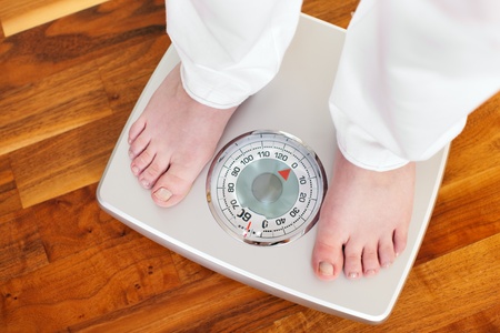 Woman (only feet to be seen) standing on bathroom scale measuring her weight controlling her dieting results の写真素材