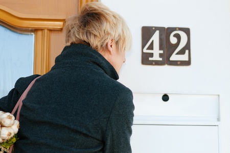 Woman with her groceries looking in her letter boxの写真素材