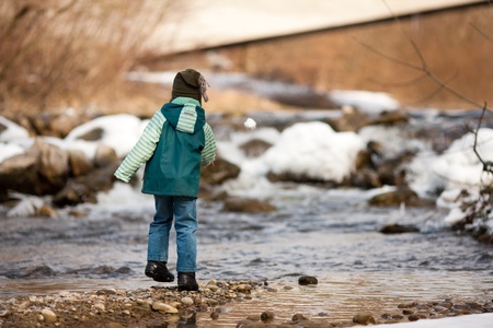 Little boy on a walk along a riverbank in winter; the child is standing on the iceの写真素材