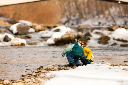 Little boys playing on a riverbank in winter  の写真素材