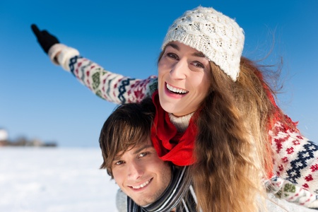 Couple - man and woman - having a winter walk; he is carrying herの写真素材