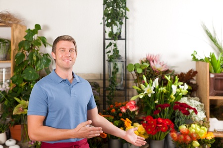 Male Florist in flower shop or nursery presenting his plants on displayの写真素材