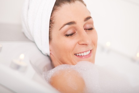 Young woman takes a pampering bath with lots of bubbles 