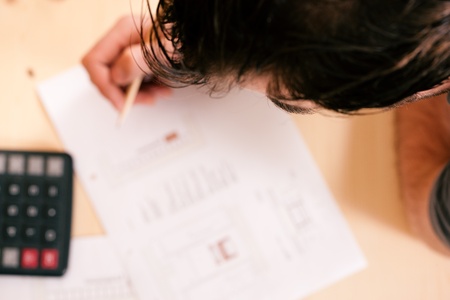 Carpenter planning his work - man thinking with set of tools, pencil, calculator and blueprint 