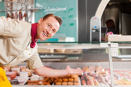 Portrait of confident butcher presenting fresh meat at his shopの写真素材
