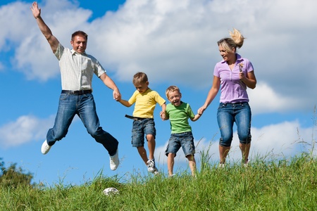 Happy family with children jumping in a meadow in summerの写真素材
