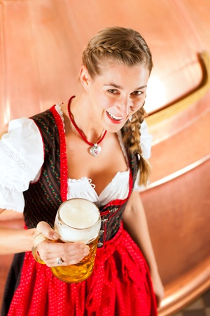 Woman in Bavarian Tracht, a female brewer, with beer stein in breweryの写真素材