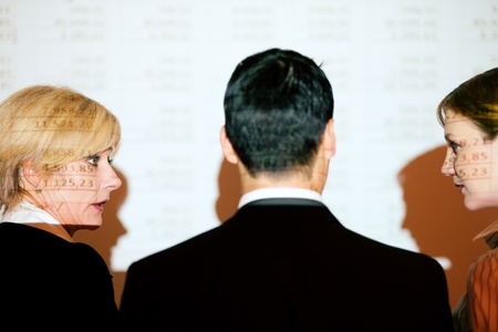 Group of people in front of a spreadsheet projected on wall  people only illuminated by projector, there are wirelines from projection on people and screen, selective focus on hand of presenter  の写真素材