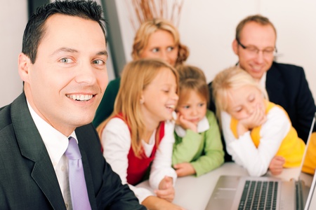 Family with their consultant  assets, money or similar  doing some financial planning - symbolized by a piggy bank in the front, the consultant in front looking at the cameraの写真素材
