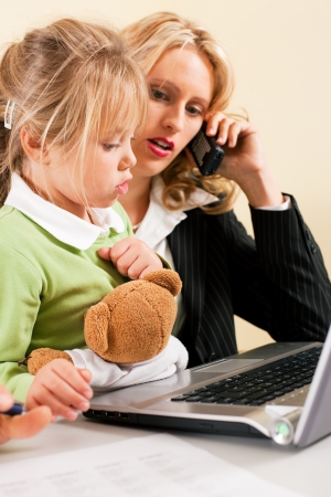 Family Business - telecommuter Businesswoman and mother showing her little daughter how these computer and internet things workの写真素材