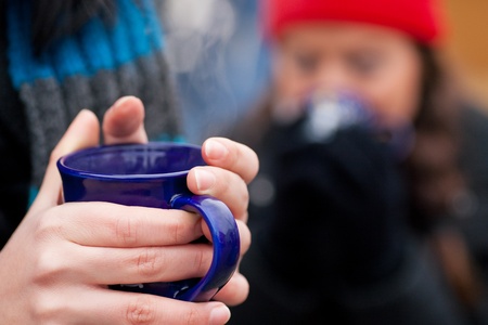 People on a Christmas market drinking punch or hot spiced wine, it is cold and they have a need to...
