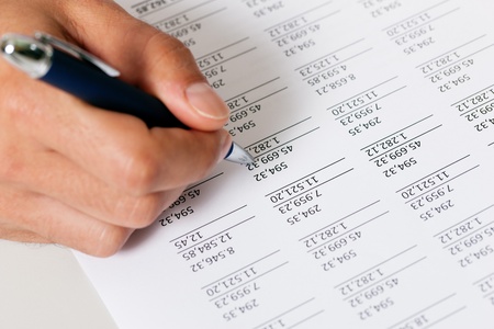 Man  only hand to be seen, presumably an accountant  working on a document with numbersの写真素材