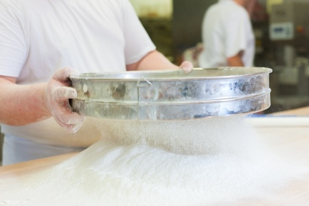 Male baker baking fresh bread in the bakehouse
