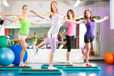 Fitness - Young women doing sports training or workout with stepper in a gymの写真素材