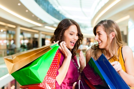 Two female friends with shopping bags having fun while shopping in a mallの写真素材