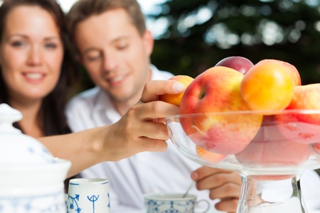Young couple drinking coffee in their garden on a beautiful summer dayの写真素材