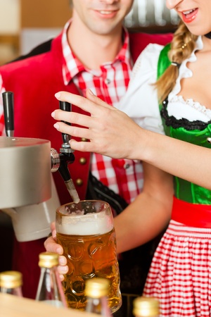 Young woman drawing beer in restaurant or pub, she is the innkeeperの写真素材
