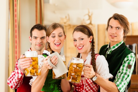 Young people in traditional Bavarian Tracht in restaurant or pub with beer and steinsの写真素材
