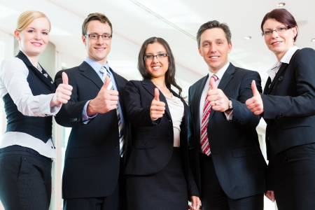 Business - group of businesspeople posing for group photo in office showing thumbs up Business - group of businesspeople posing for group photo in office showing thumbs up