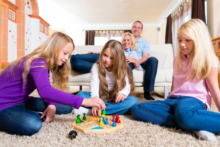 Family playing board game ludo at home on the floorの写真素材