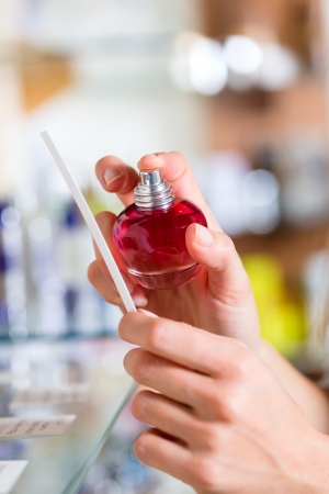 Young woman (only hands to be seen) buying perfume in a shop or store, testing the fragrance with a paper testerの写真素材