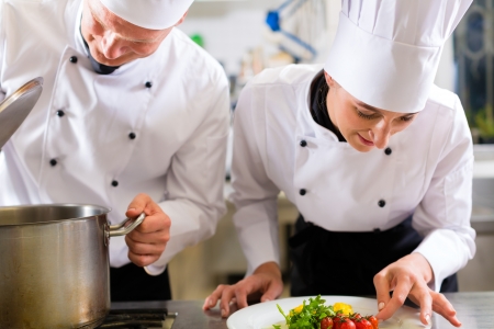 Two chefs - man and woman - in hotel or restaurant kitchen working and cooking in teamの写真素材