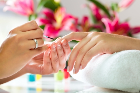 Woman in a nail salon receiving a manicure by a beautician Woman in a nail salon receiving a manicure by a beautician