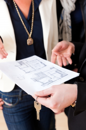 Young realtor explain ground plan to couple in an apartmentの写真素材
