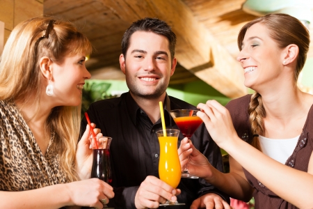 Young happy people drinking cocktails in bar or restaurant; presumably it is a little partyの写真素材