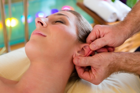 Woman enjoying head massage or lymphatic drainage in a spa の写真素材