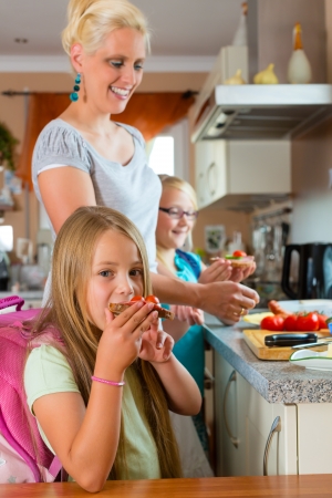 Family - mother making breakfast for her children in the morning and a snack for schoolの写真素材
