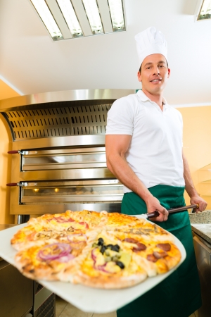 Man pushing the finished pizza from the oven with the pizza shovelの写真素材