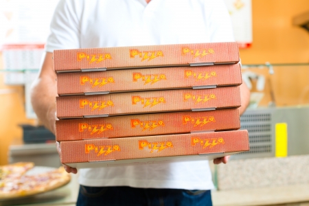 Man holding several pizza boxes in hand ready for deliveryの写真素材