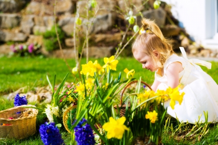 Little Girl on an Easter Egg hunt on a meadow in spring, she has found an Easter eggの写真素材