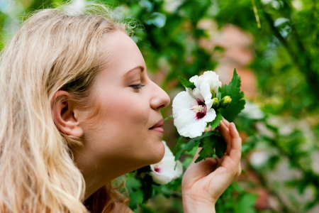 Very beautiful Woman in her garden taking a sniff at some flowersの写真素材