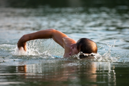 Very athletic man swimming in a wonderful soft late afternoon lightの写真素材