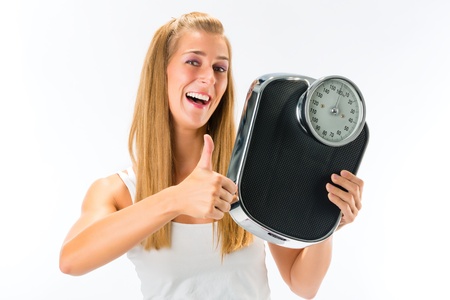 Diet and weight, young woman with a weight scale, she is happy about her successの写真素材