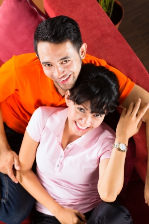 Indonesian couple sitting cozy at home on the sofa and relaxingの写真素材