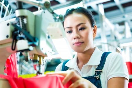 Seamstress or worker in a factory sewing with a industrial sewing machine, she is very accurateの写真素材