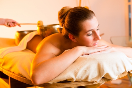 Woman in wellness and spa setting having a singing bowl massage therapyの写真素材