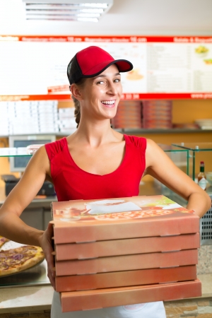 Woman holding several pizza boxes and smilingの写真素材