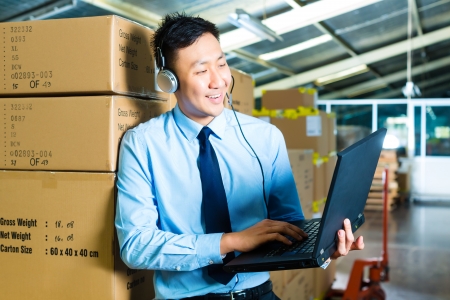 Young man in a suit with headset and laptop in a warehouse, he is from the Customer Serviceの写真素材