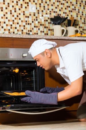 Asian man baking homemade cake in his kitchen for dessertの写真素材