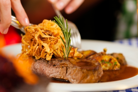 Someone eating beef roast in Bavarian restaurant or pub for lunch or dinnerの写真素材